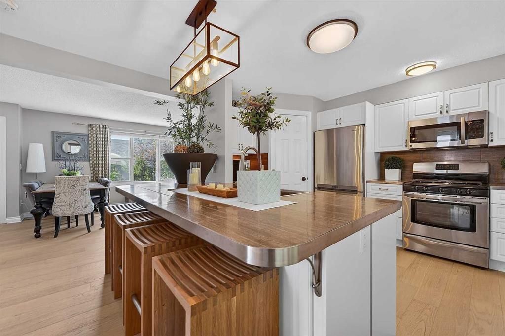 Bright open kitchen with granite island, stainless appliances, and a dining area by large windows.