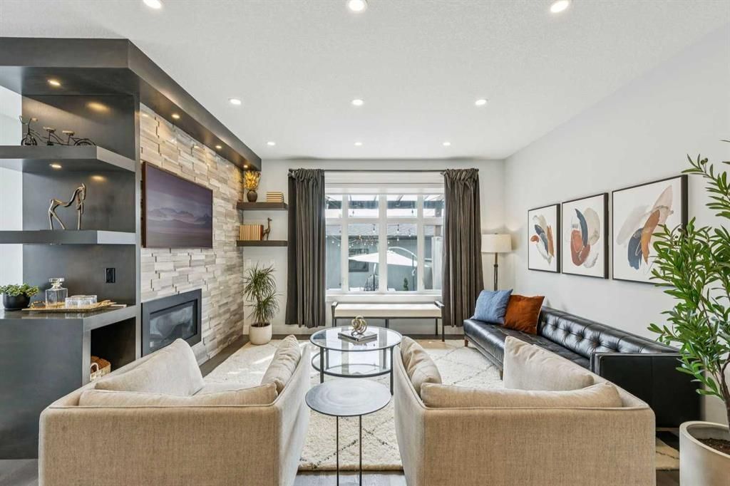 Bright modern living room with beige sofas, fireplace, TV, and a windowed dining area