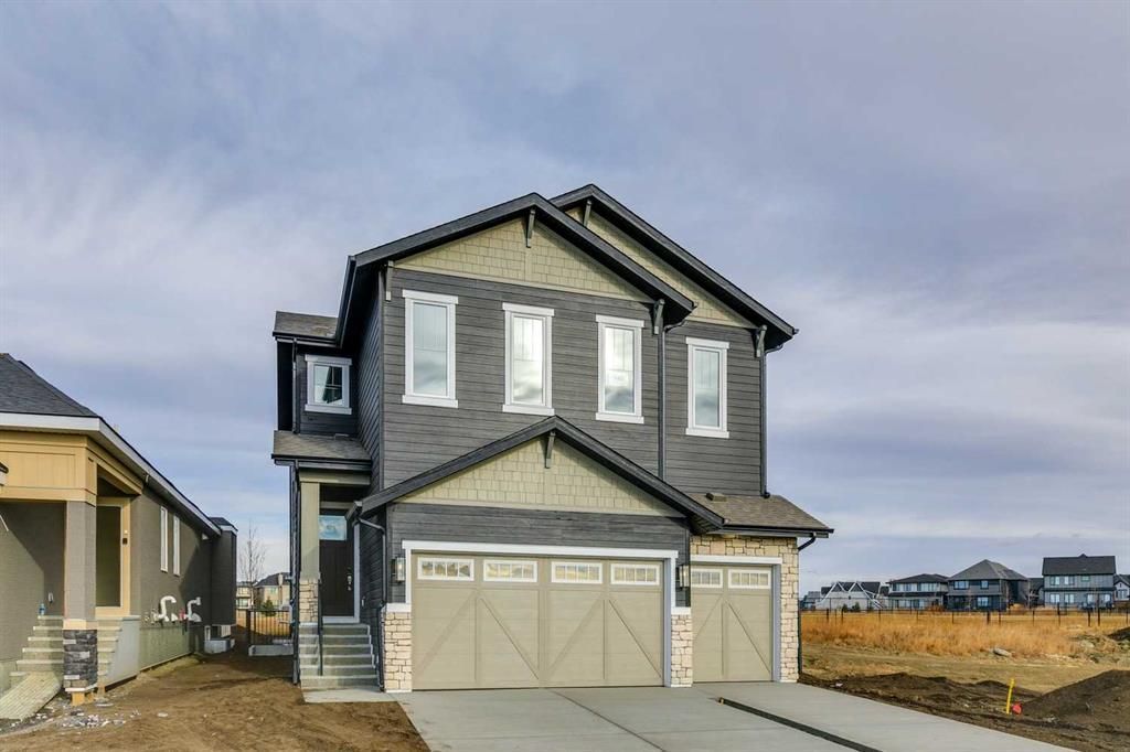 Two-story gray house with light-colored garage doors, set against a cloudy sky.