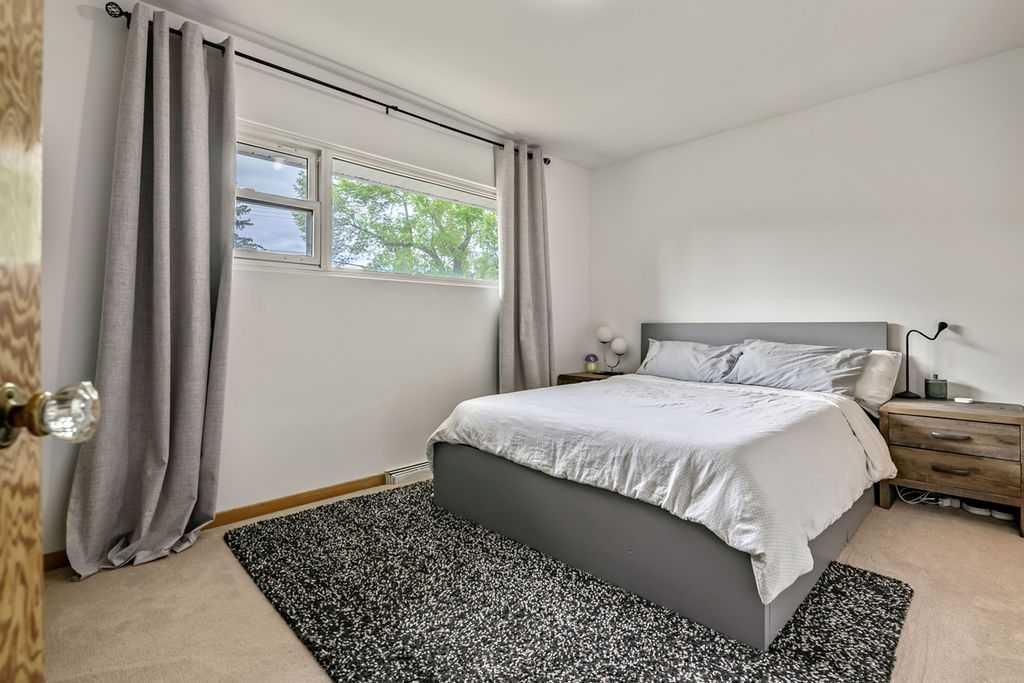 Bright bedroom with a bed, gray curtains, and a window letting in daylight