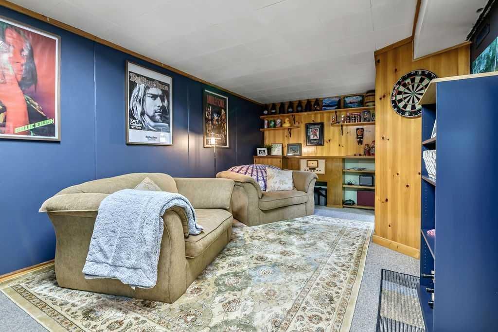 Cozy bedroom with blue walls, two beds, patterned rug, framed art, and wooden cabinets.