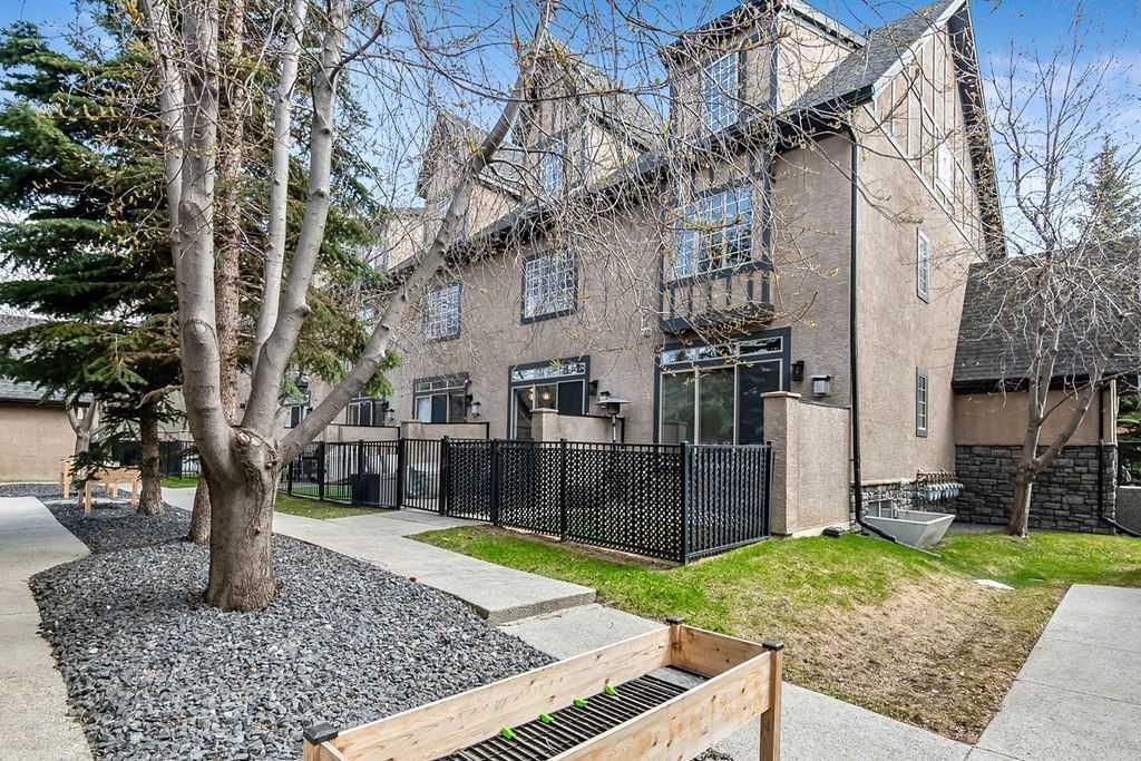 Modern townhouse exterior with trees, gravel landscaping, and a walkway on a sunny day