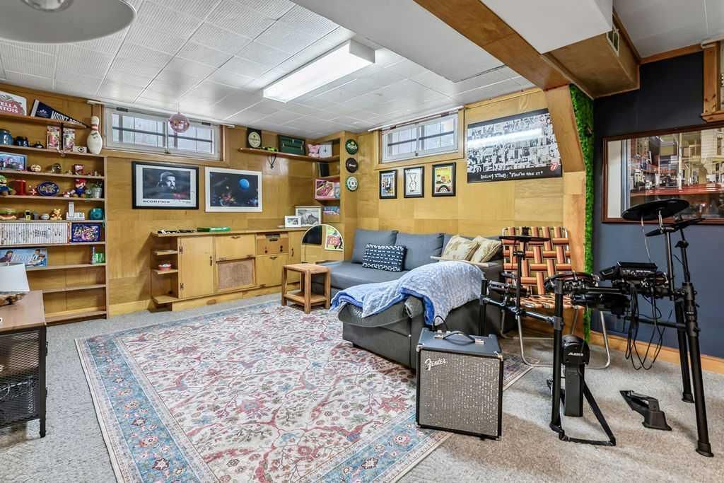 Cozy music room with instruments, shelves of records, wall art, couch, and large rug