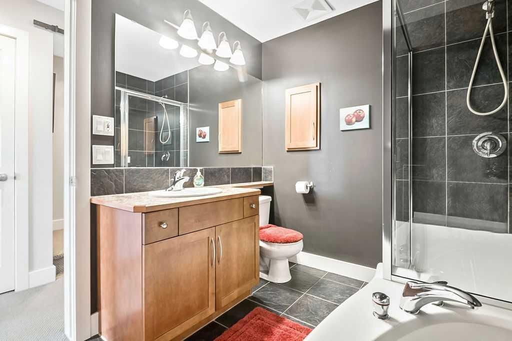 Modern bathroom with wood vanity, mirror, bathtub, and gray walls