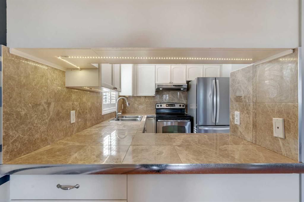 Modern kitchen pass-through with granite countertops and stainless steel appliances