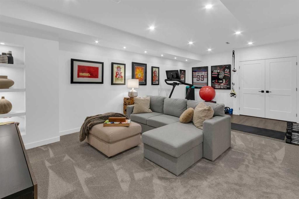 Modern living room with gray sectional, beige ottoman, wall art, and recessed lighting