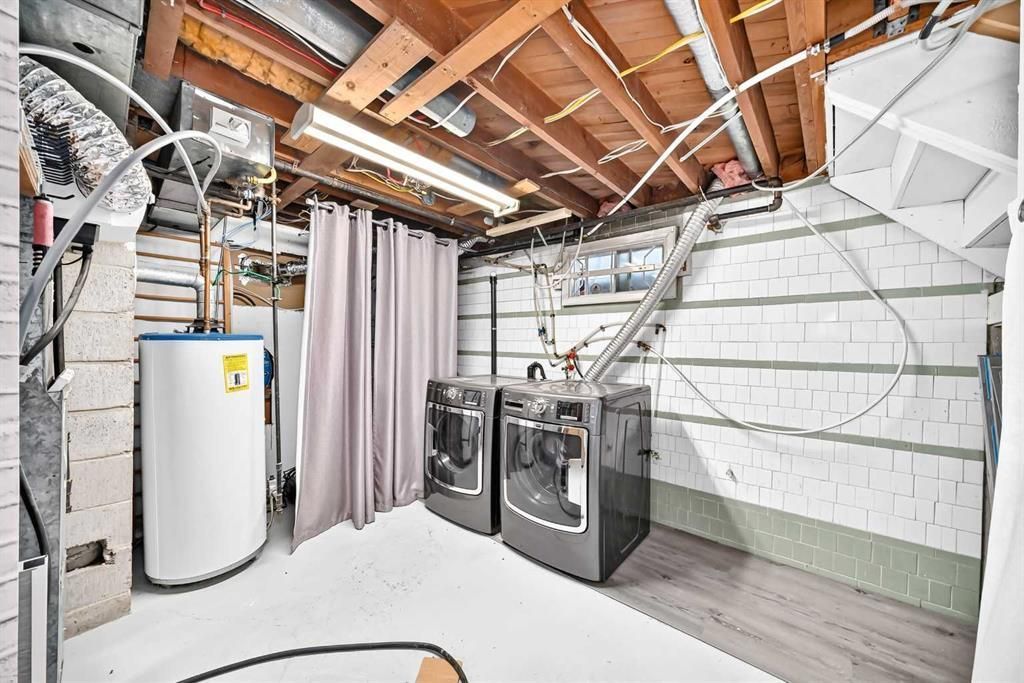 Laundry room with washer, dryer, and water heater in a partially finished basement
