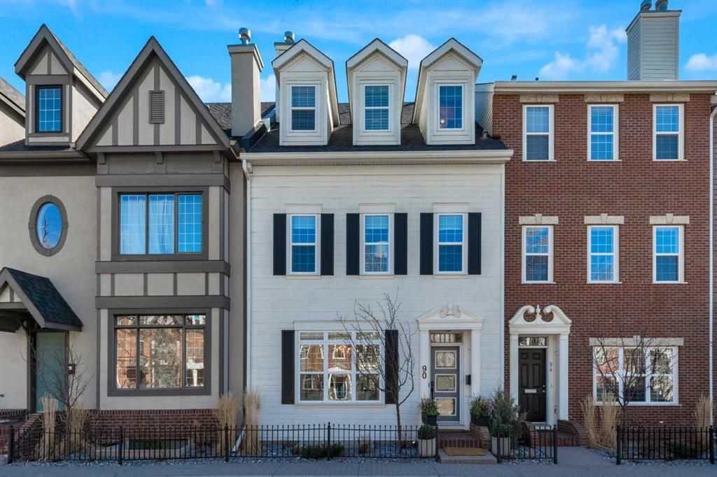 Row of colorful townhouses with dormer windows and brick facades on a city street