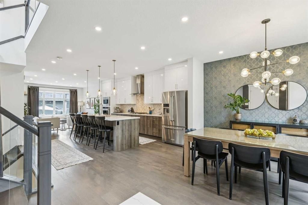 Bright open-concept kitchen and dining area with marble island, black chairs, and pendant lights