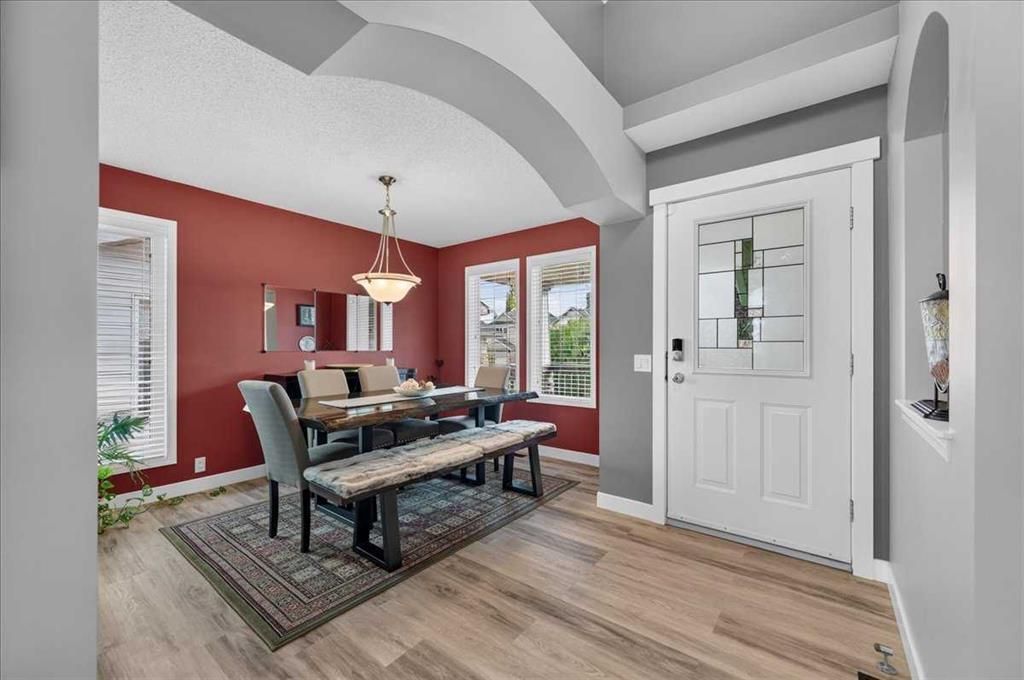 Dining room with red accent wall, black table, chairs, and front entry door