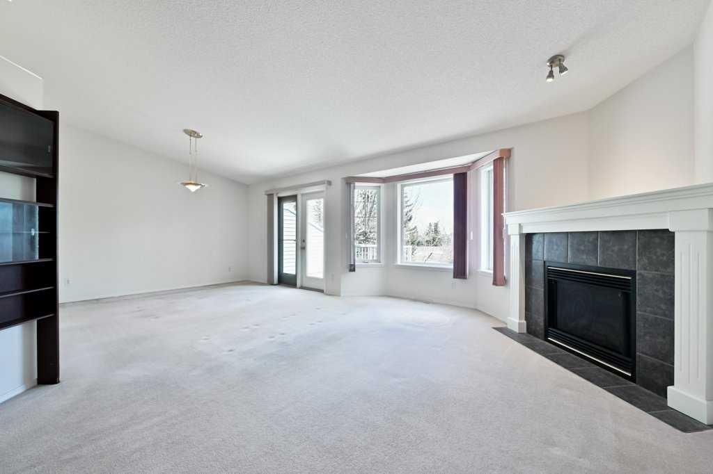 Bright empty living room with carpet, fireplace, and large windows