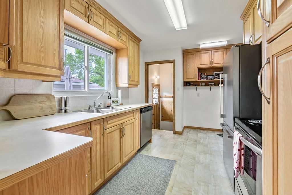 Bright kitchen with wood cabinets, white countertops, a window over the sink, and a black refrigerator.