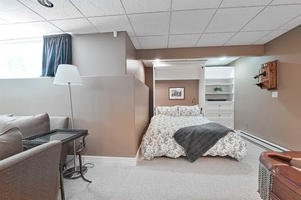 Basement bedroom with a bed, couch, floor lamp, and small shelving unit.