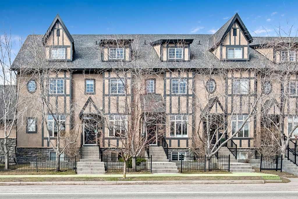 Row of gray townhouse-style apartment buildings with peaked roofs and bare trees in front