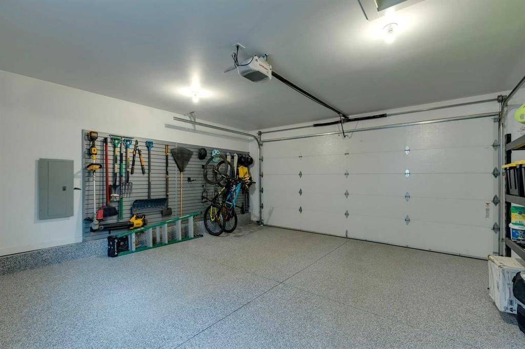 Bright garage interior with tools on the wall, bicycles, and a closed white double garage door.