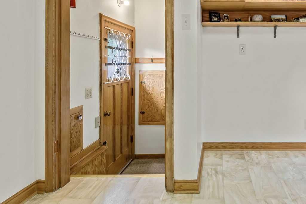 Hallway with wood trim, open doorway, and a built-in coat rack on a white wall