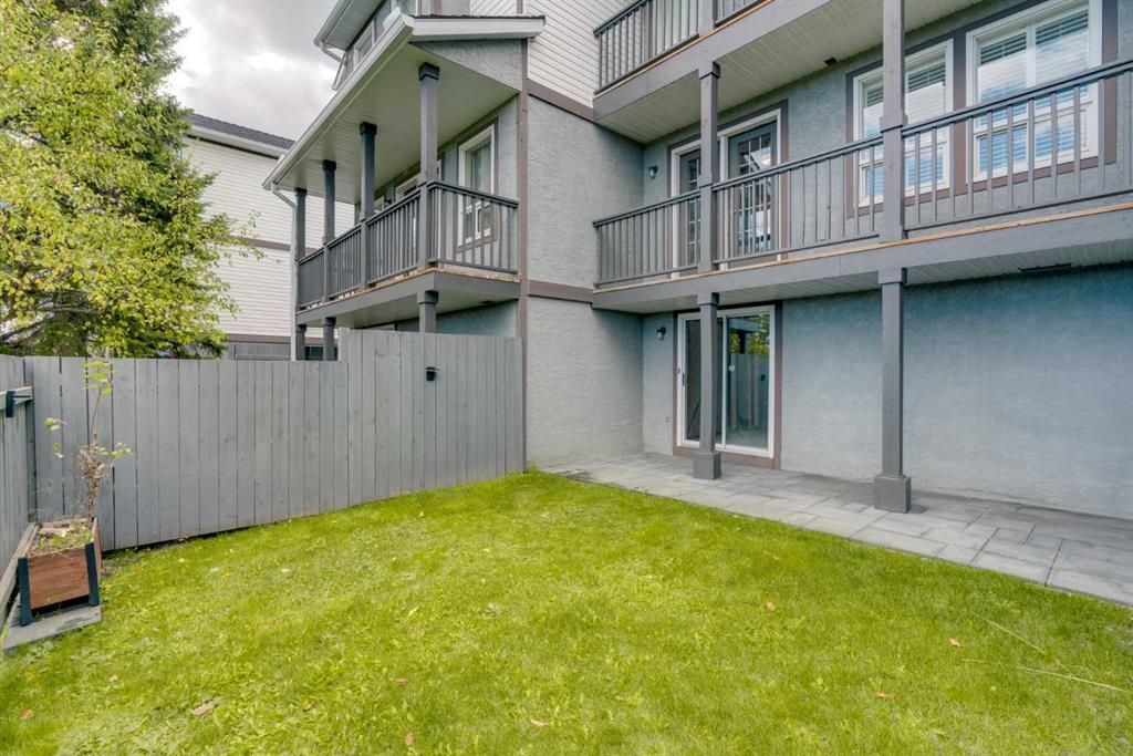 Apartment building courtyard with green lawn, gray fence, and balconies above