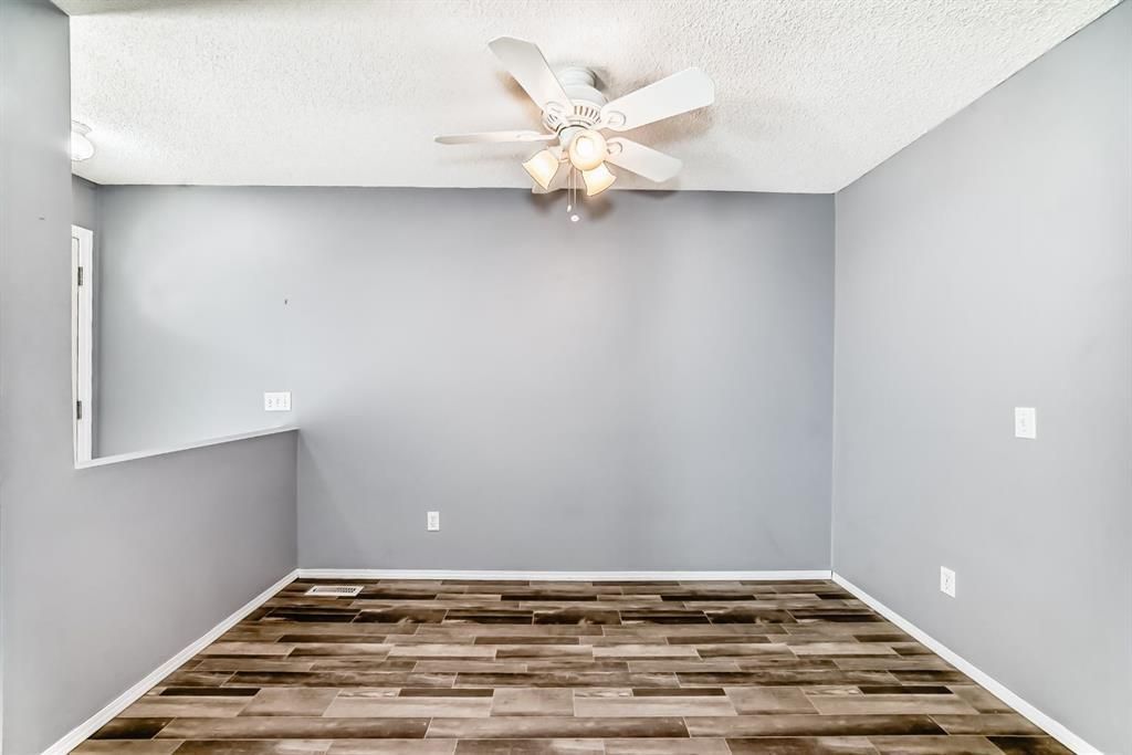 Empty gray room with wood-pattern flooring and a ceiling fan under a white ceiling