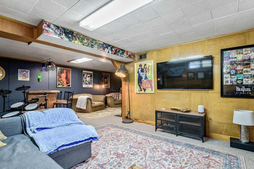 Basement recreation room with TV, couch, desk, and colorful wall decor