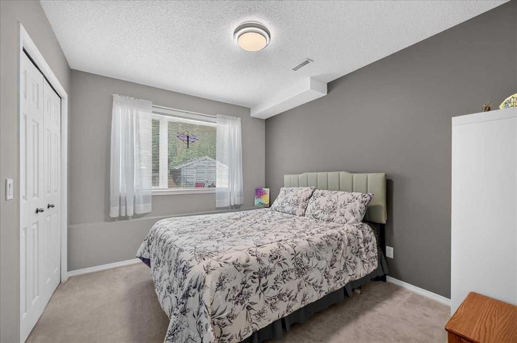 Bright bedroom with gray walls, a bed by the window, and white closet doors