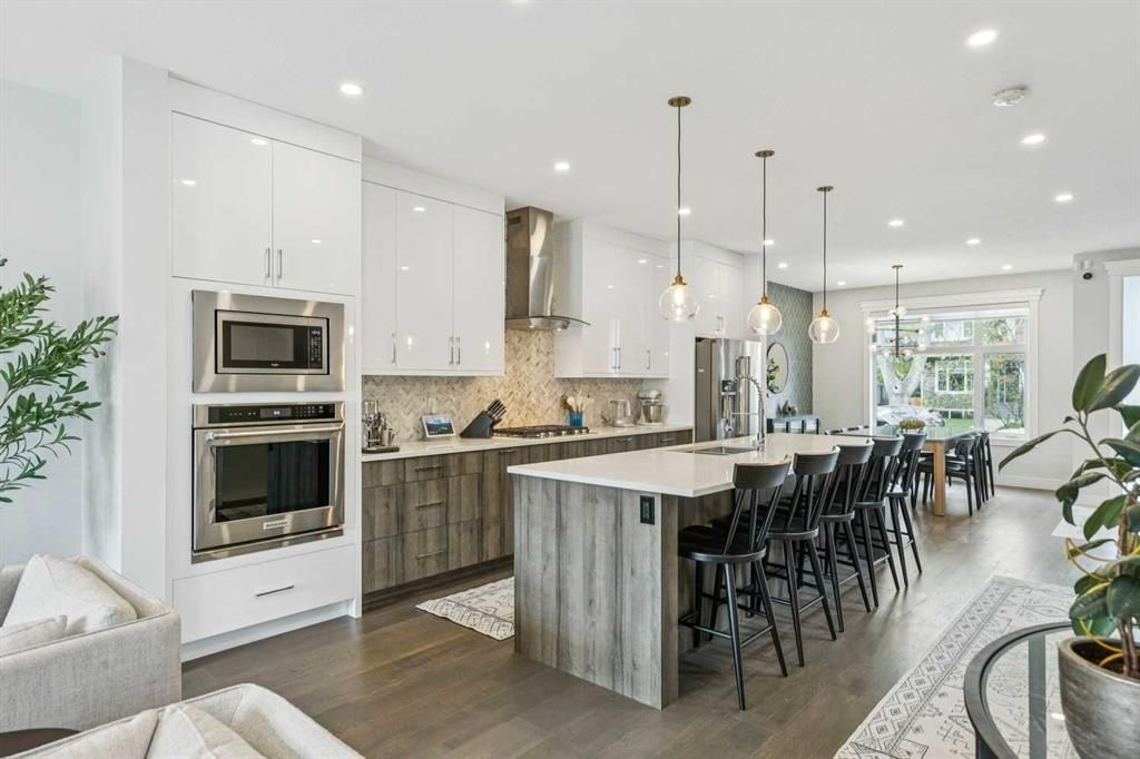 Bright modern kitchen with white cabinets, dark island, pendant lights, and black barstools