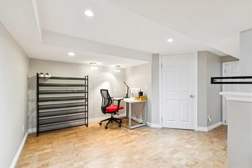 Bright home office with a desk, red chair, clothing rack, and white closet doors on wood floors