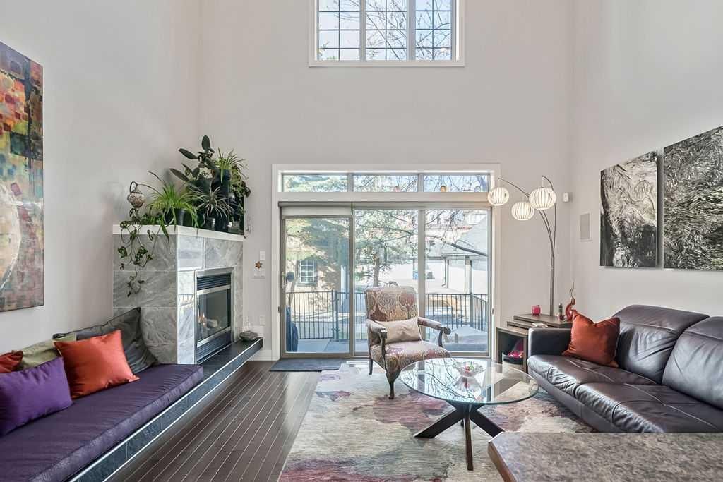 Bright living room with black sofas, glass coffee table, fireplace, and large sliding doors to a patio