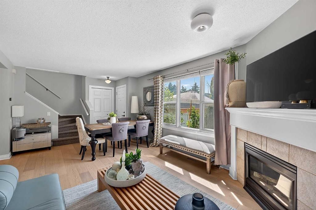 Bright modern living room with large windows, dining table, sofa, coffee table, and fireplace