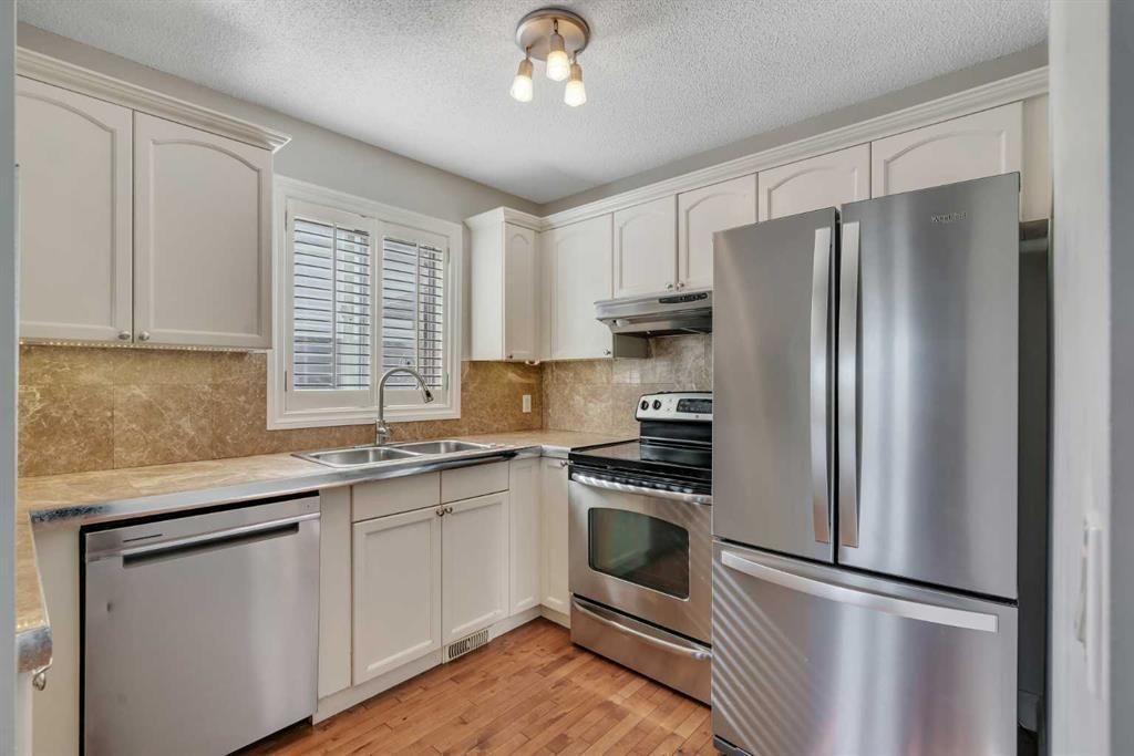 Bright kitchen with white cabinets, stainless steel appliances, and wood floors