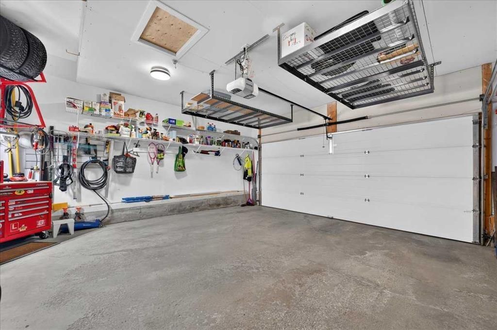 Clean garage interior with white walls, concrete floor, workbench, tools, and a closed garage door.