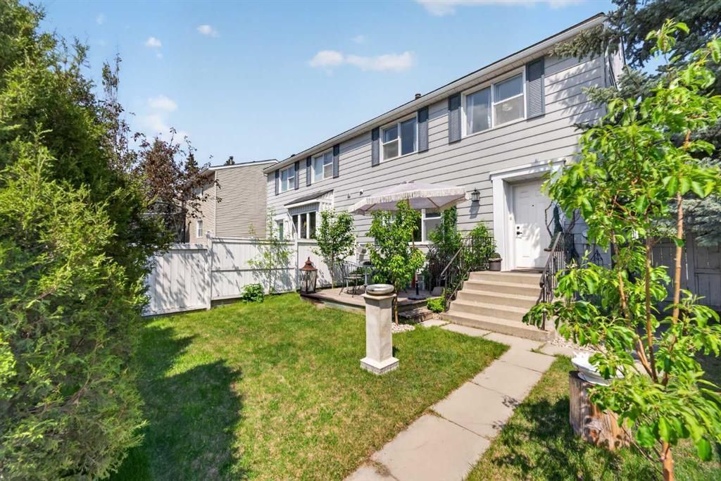 Sunny apartment courtyard with green lawn, walkway, and two-story building exterior