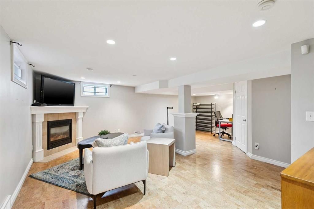 Bright living room with white furniture, fireplace, TV, and staircase in an open floor plan.