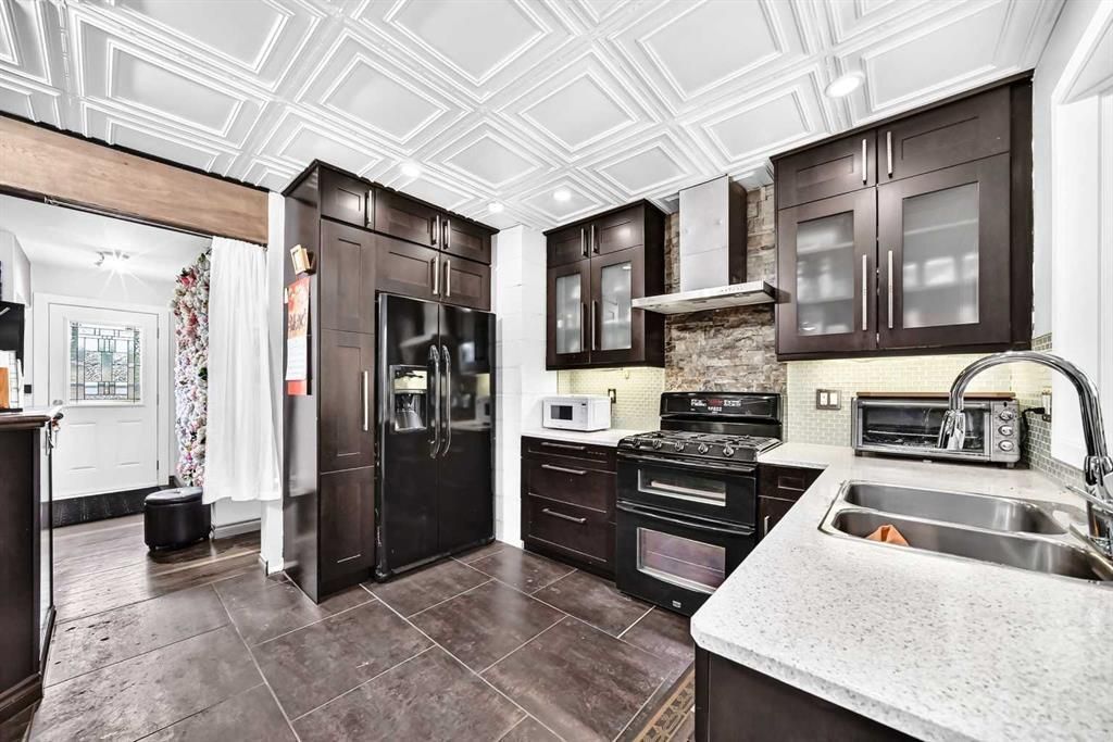Bright kitchen with dark wood cabinets, black appliances, and white countertops and ceiling.