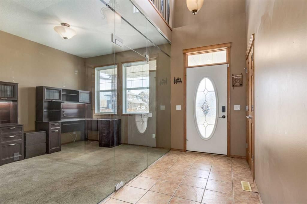 Spacious kitchen with tan tile floor, dark cabinets, and a white front door with oval glass window.