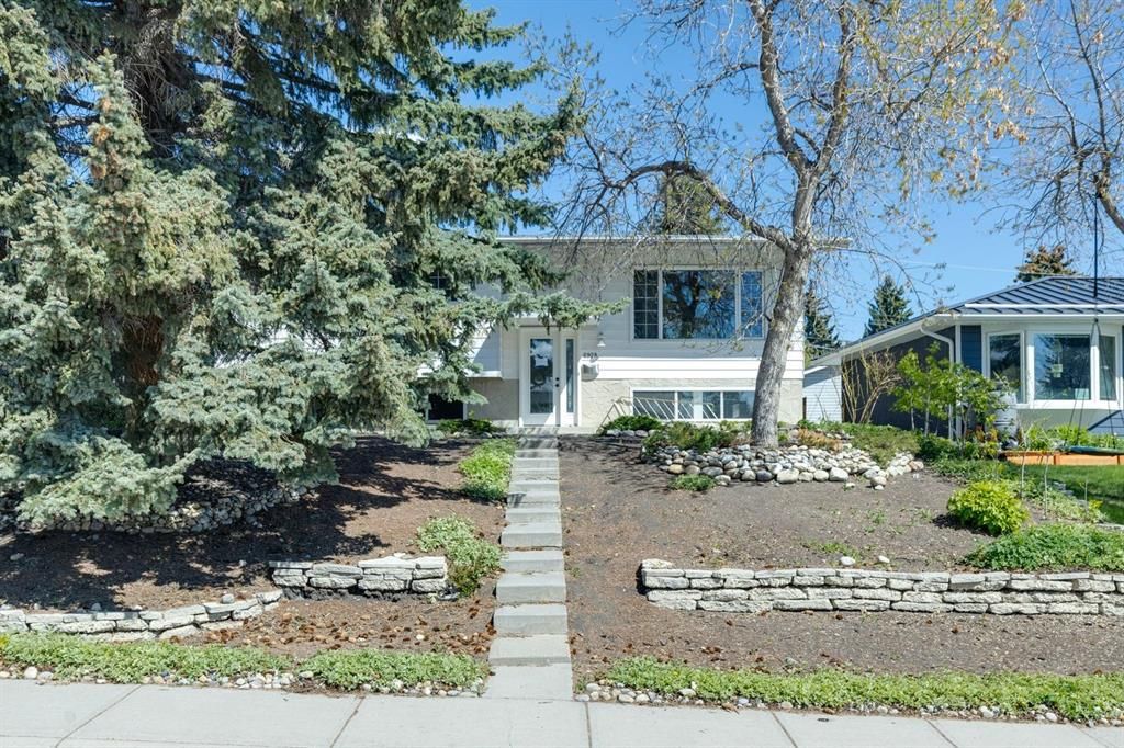 Landscaped front yard with stone steps leading to a white house under a blue sky
