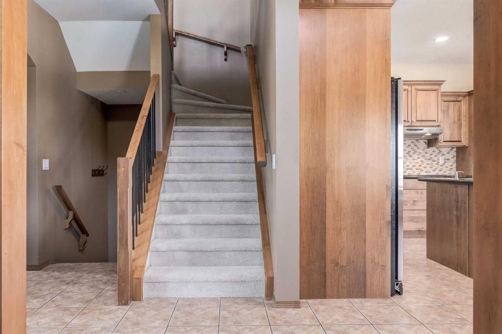 Interior staircase with carpeted steps, wood railing, and kitchen visible to the right.