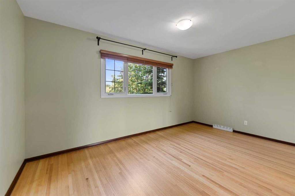 Empty beige room with hardwood floor and a window letting in daylight