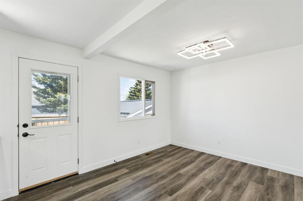 Empty white room with wood-look flooring, a door, and a window letting in natural light