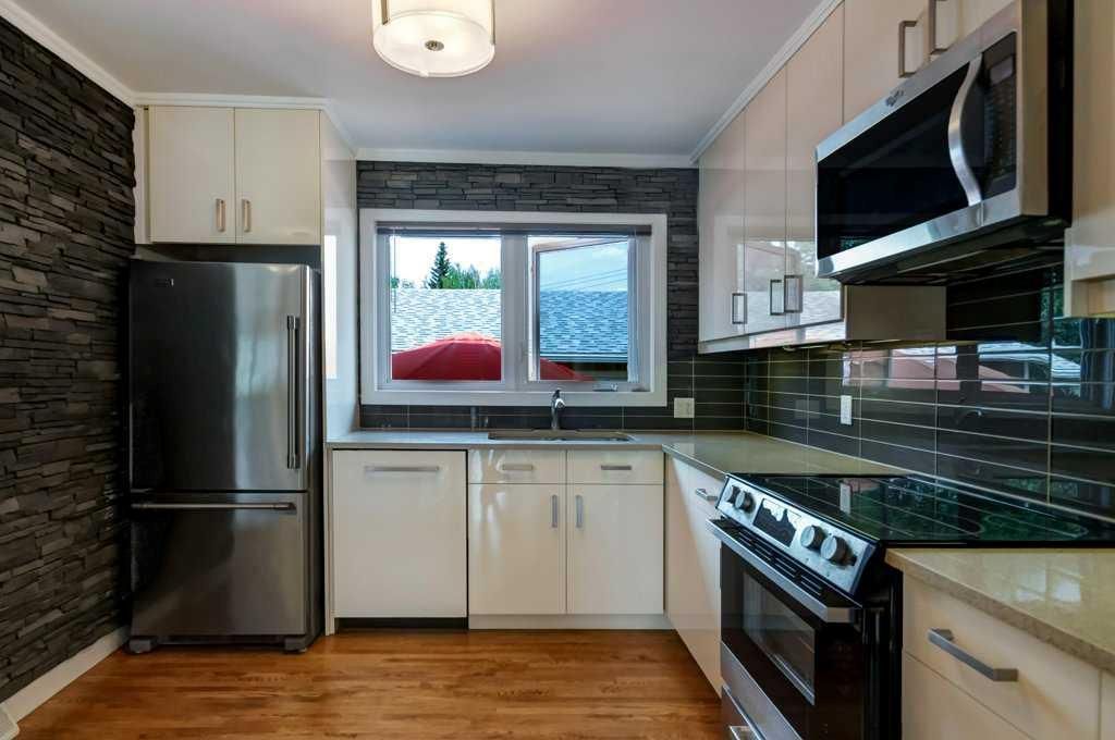 Modern kitchen with stainless steel appliances, white cabinets, and a window over the sink.