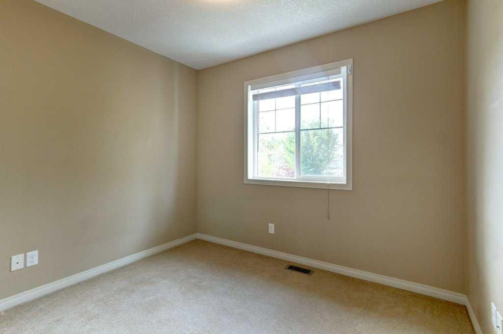Empty beige bedroom with carpet, a window, and white trim