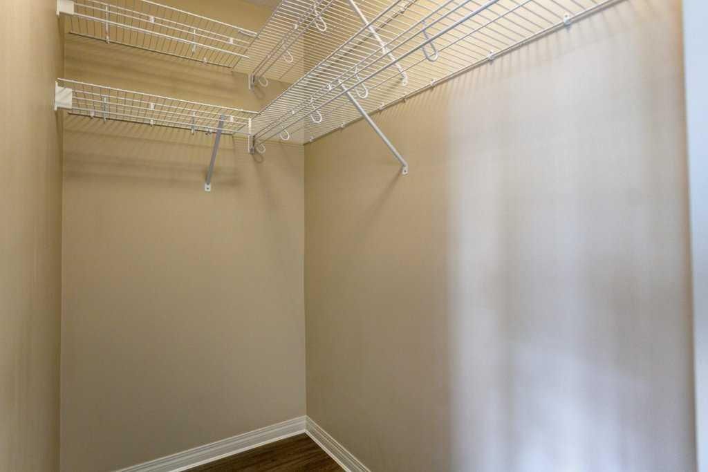 Empty beige closet with wire shelving and hanging rods on the ceiling and walls
