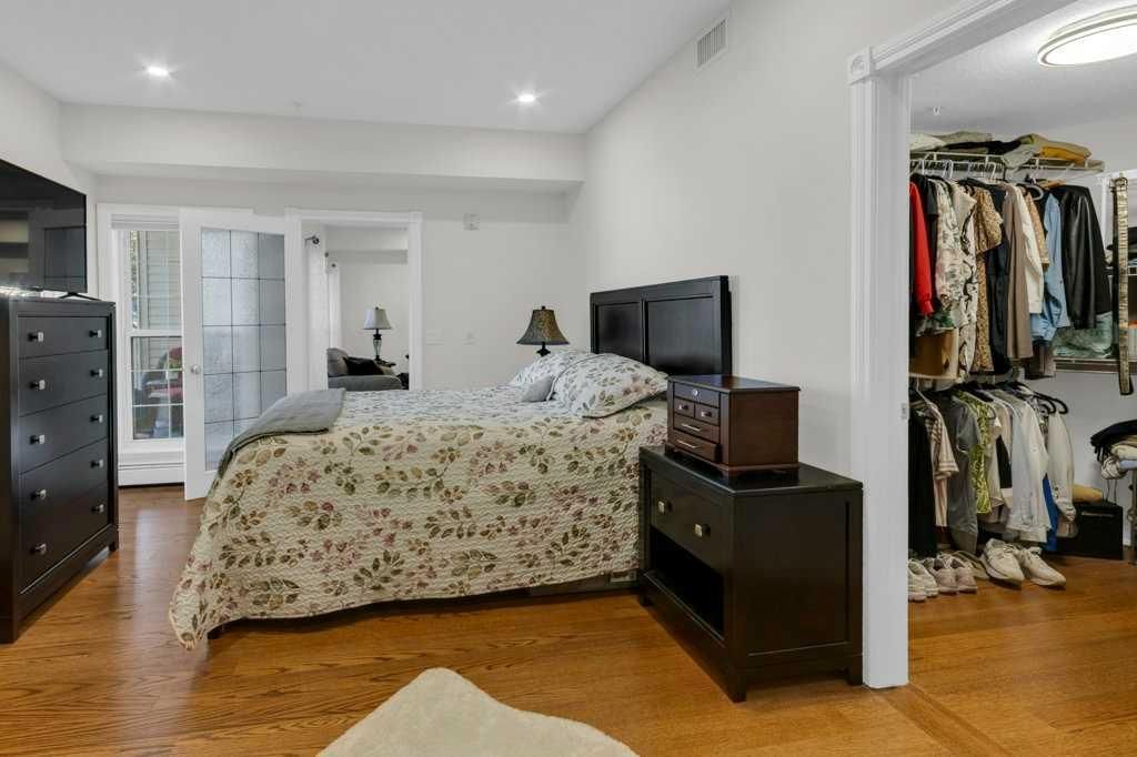 Bedroom with bed, dresser, TV, and open closet in a bright hardwood-floored room
