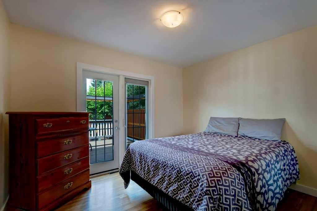 Bedroom with bed, dresser, and glass doors opening to a balcony