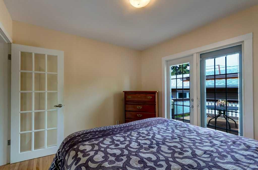 Bedroom with patterned bedspread, dresser, and French doors leading to a balcony.