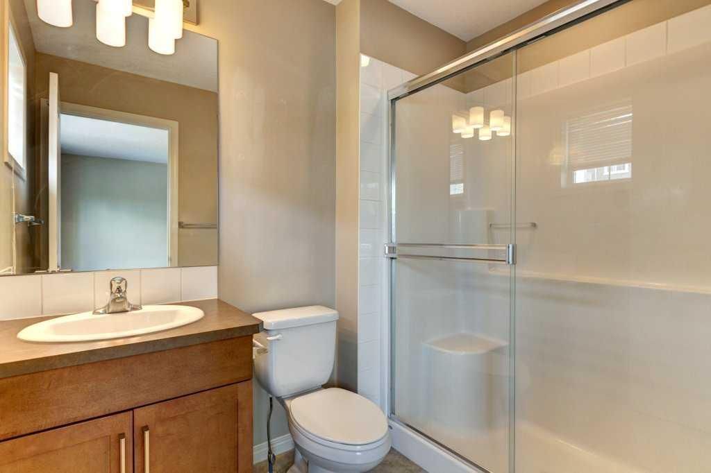 Small bathroom with a vanity, toilet, and glass-enclosed shower in beige tones.