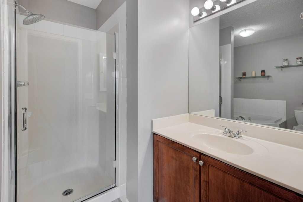 Bright bathroom with a shower stall, white vanity, and large mirror