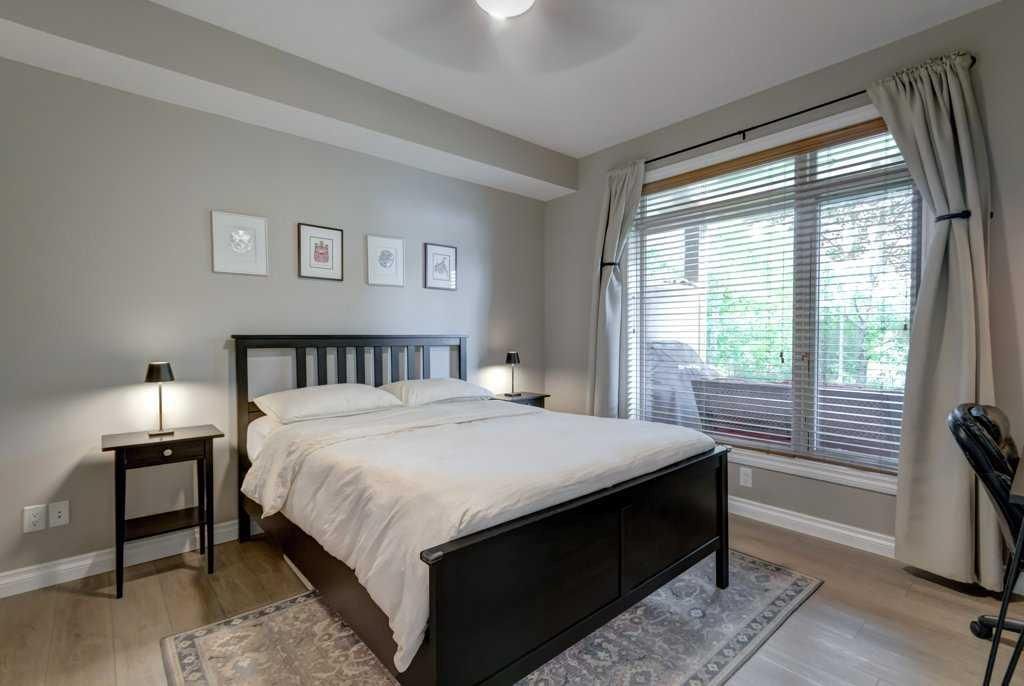 Bright bedroom with white bedding, vanity desk, mirror, closet, and open bathroom doors.