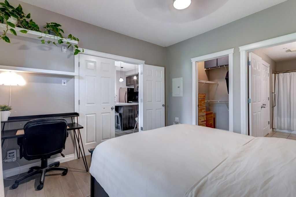 Bright bedroom with bed, window seat, desk, and open double doors to a hallway