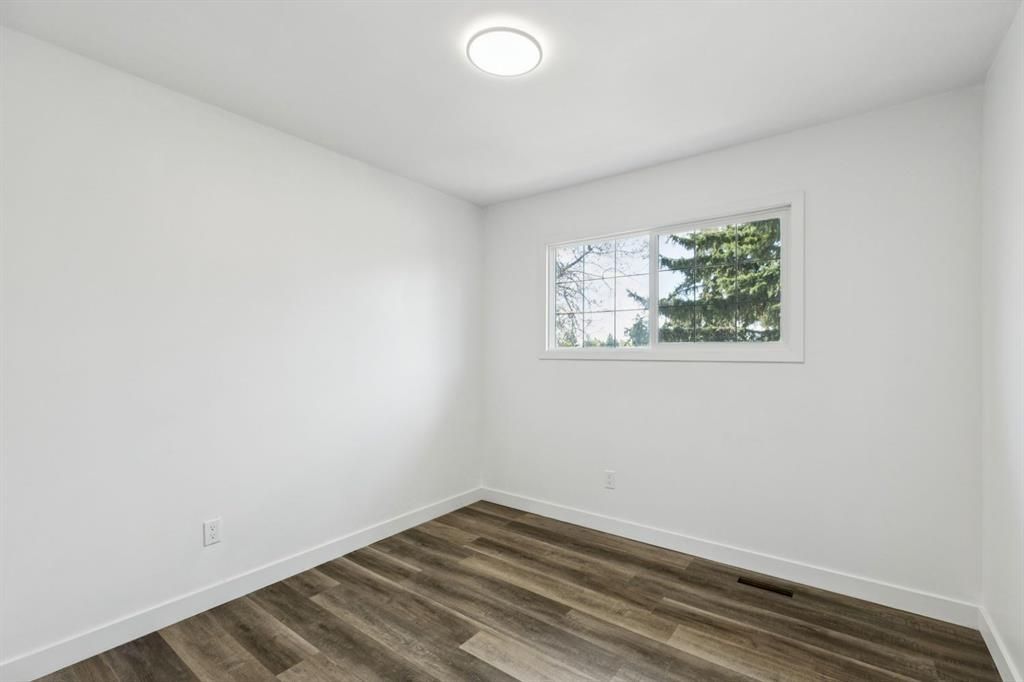 Empty white room with wood floors and a small window.