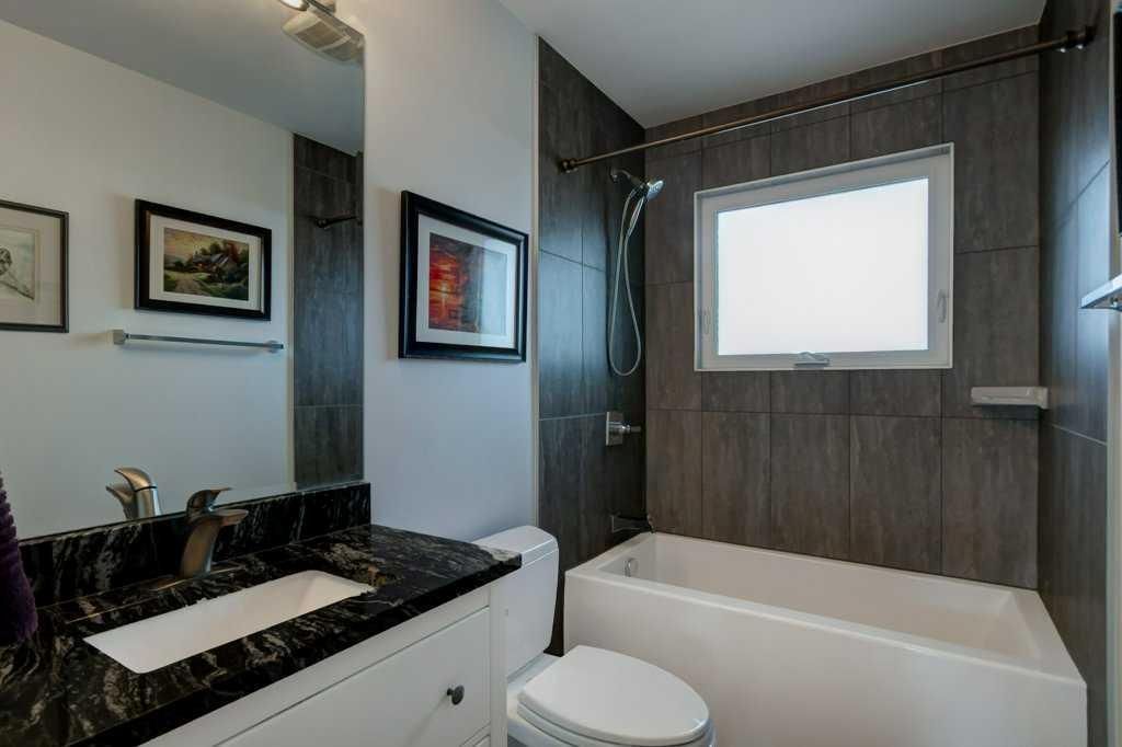Modern bathroom with bathtub, window, dark wood paneling, and black countertop sink